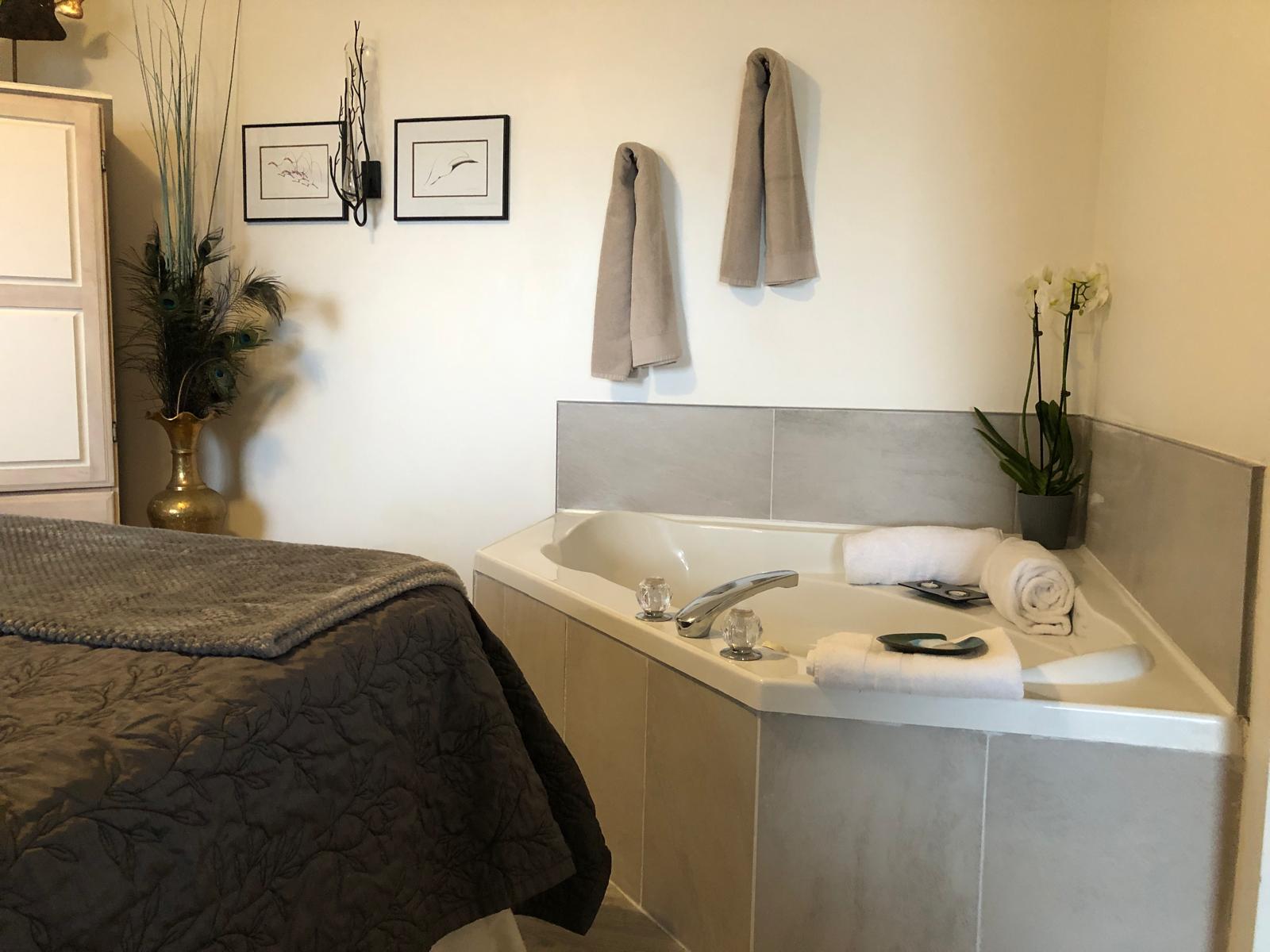 Cozy in-room Jacuzzi in the Oceanside Honeymoon Suite at Qualicum Breeze Resort, featuring elegant decor, towels, and a decorative plant.