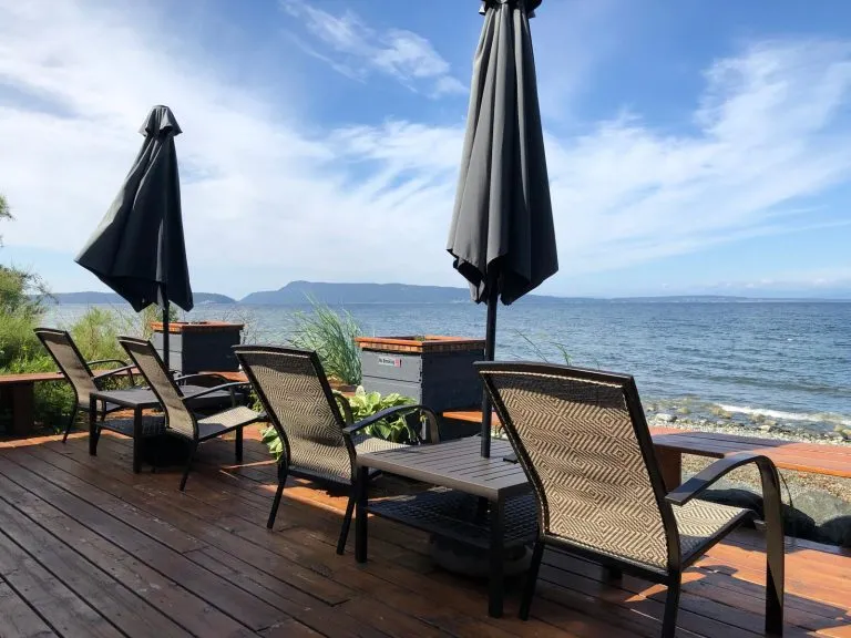 Lounge chairs with umbrellas on a wooden deck overlooking the ocean.
